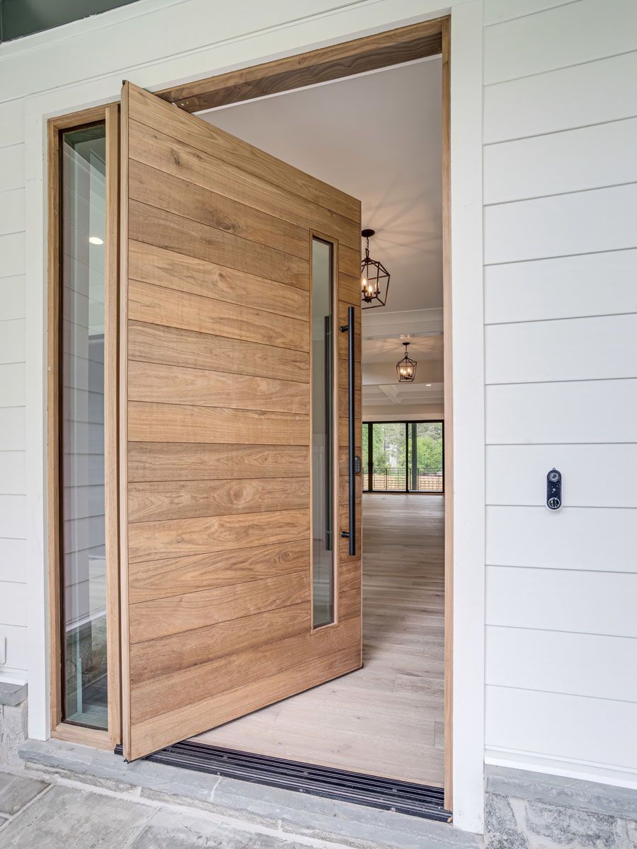 The Katti pivot door in warm honey-toned walnut, in a farmhouse-style home.