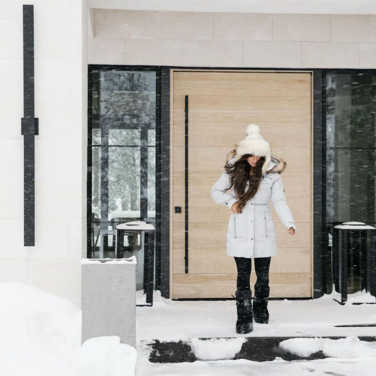The Solace pivot door in light, warm-toned white oak, in a snowy mountain home.