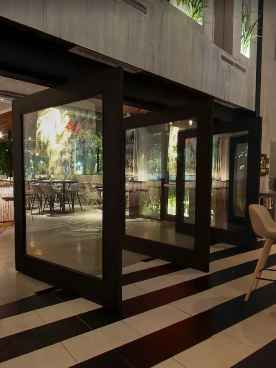 A pivot door in a black paint finish, installed in a restaurant.